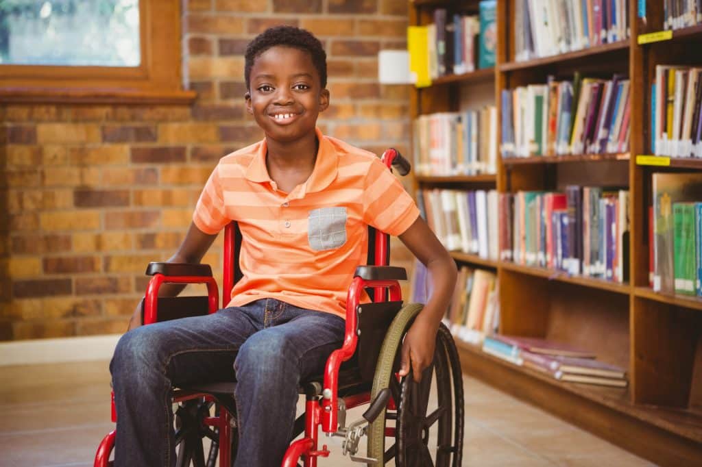 Portrait of little boy sitting in wheelchair at the library