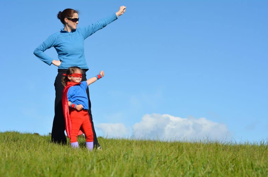 Superhero mother and daughter against dramatic blue sky background with copy space. concept photo of Super hero, girl power, play pretend, childhood, imagination.