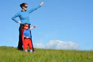 Superhero mother and daughter against dramatic blue sky background with copy space. concept photo of Super hero, girl power, play pretend, childhood, imagination.